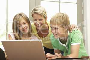 Mother And Teenage Children Using Laptop At Home