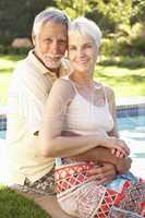 Senior Couple Relaxing By Pool In Garden