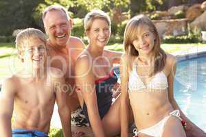 Young Family Relaxing By Pool In Garden