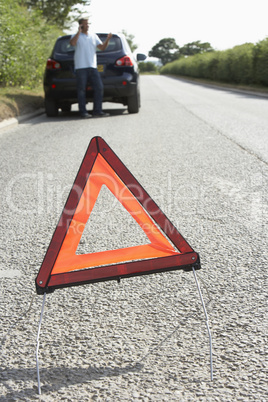 Driver Broken Down On Country Road With Hazard Warning Sign In F