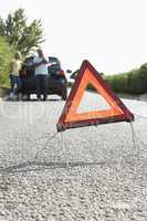 Couple Broken Down On Country Road With Hazard Warning Sign In F