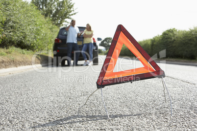 Couple Broken Down On Country Road With Hazard Warning Sign In F