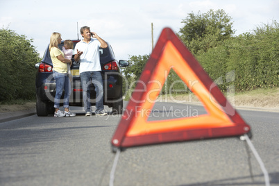 Family Broken Down On Country Road With Hazard Warning Sign In F