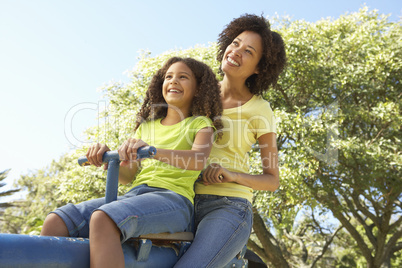 Mother And Daughter Riding On Seesaw In Park