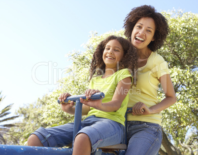 Mother And Daughter Riding On Seesaw In Park