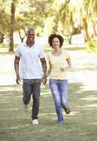 Portrait Of Young Couple Running Through Park