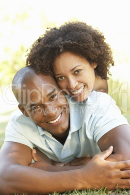 Portrait Of Young Couple Laying On Grass In Park