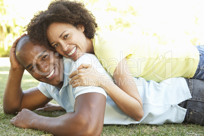 Portrait Of Young Couple Laying On Grass In Park