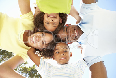 Portrait of Happy Family Looking Down Into Camera In Park