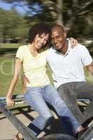 Young Couple Riding On Roundabout In Park