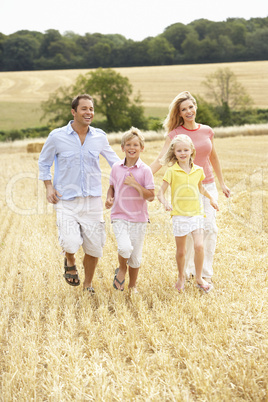 Family Running Together Through Summer Harvested Field