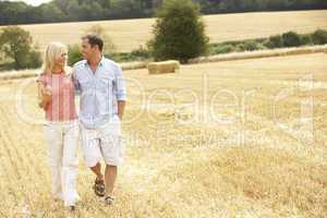Couple Walking Together Through Summer Harvested Field