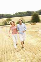 Couple Running Together Through Summer Harvested Field