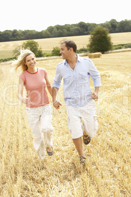 Couple Running Together Through Summer Harvested Field