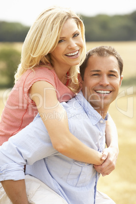 Couple Having Piggyback In Summer Harvested Field