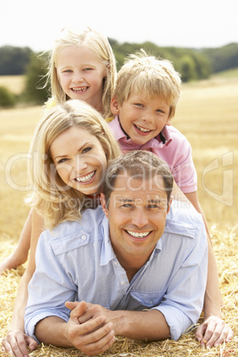 Family Relaxing In Summer Harvested Field