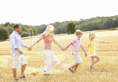 Family Walking Together Through Summer Harvested Field