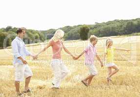 Family Walking Together Through Summer Harvested Field