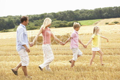 Family Walking Together Through Summer Harvested Field