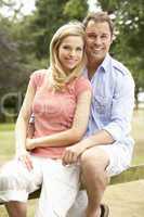 Couple Relaxing In Countryside Sitting On Fence