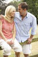 Couple Relaxing In Countryside Sitting On Fence