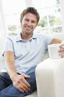 Man Sitting On Sofa Drinking Coffee Relaxing At Home
