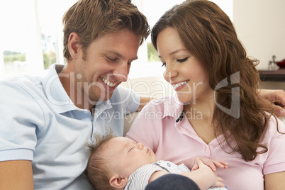 Close Up Of Parents Cuddling Newborn Baby Boy At Home