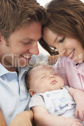 Close Up Of Parents Cuddling Newborn Baby Boy At Home