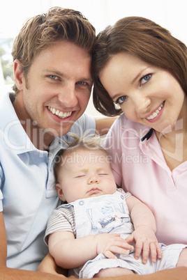 Close Up Of Parents Cuddling Newborn Baby Boy At Home