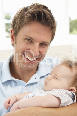 Close Up Of Father Cuddling Newborn Baby Boy At Home