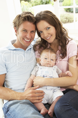 Parents Cuddling Newborn Baby Boy At Home