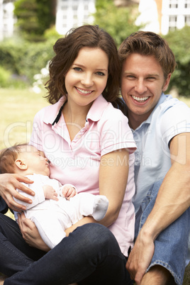 Parents Cuddling Newborn Baby Boy Outdoors At Home