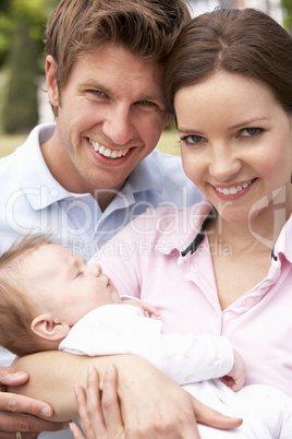 Parents Cuddling Newborn Baby Boy Outdoors At Home