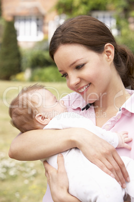 Close Up Of Mother Cuddling Newborn Baby Boy Outdoors At Home