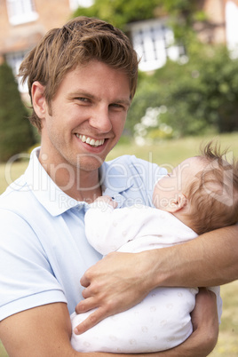 Close Up Of Father Cuddling Newborn Baby Boy Outdoors At Home