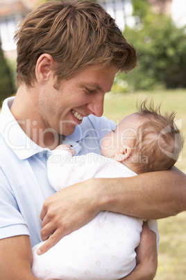 Close Up Of Father Cuddling Newborn Baby Boy Outdoors At Home