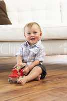 Young Boy Playing With Wooden Toy Car At Home