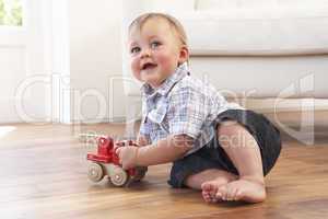 Young Boy Playing With Wooden Toy Car At Home