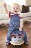 Young Boy Playing With Ride On Toy Mouse At Home
