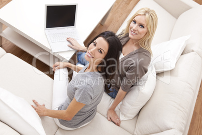 Two Young Women Using Laptop Computer At Home on Sofa