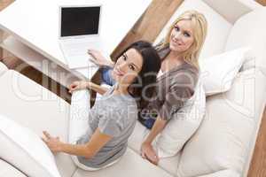 Two Young Women Using Laptop Computer At Home on Sofa