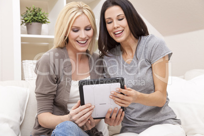 Two Young Women Using Tablet Computer At Home on Sofa