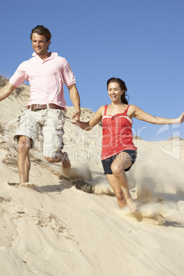 Couple Enjoying Beach Holiday Running Down Dune