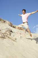 Young Man Enjoying Beach Holiday Running Down Dune