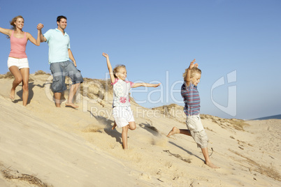 Family Enjoying Beach Holiday Running Down Dune