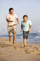 Father And Son Running Along Summer Beach
