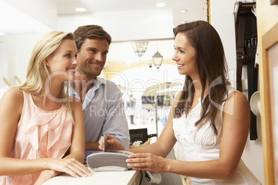 Female Sales Assistant At Checkout Of Clothing Store With Custom