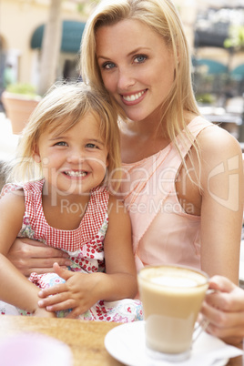 Mother And Daughter Enjoying Cup Of Coffee And Piece Of Cake In