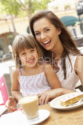 Mother And Daughter Enjoying Cup Of Coffee And Piece Of Cake In