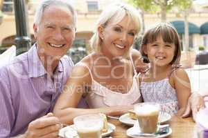 Grandparents With Granddaughter Enjoying Coffee And Cake In Caf?